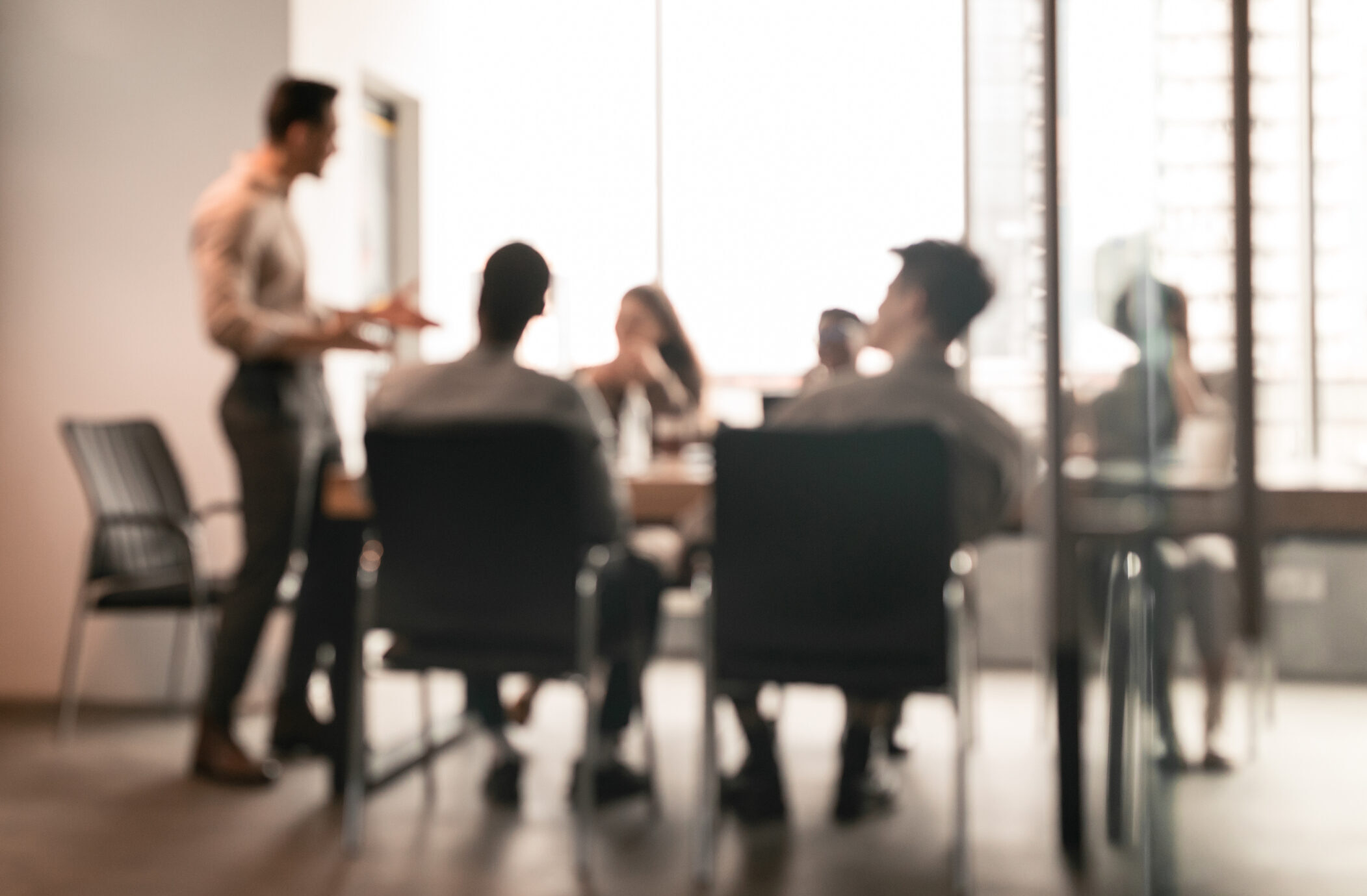 Colleagues having meeting in boardroom, businessman giving speech, blurred photo